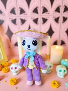 Muñeco de crochet de Don Cuco en una ofrenda festiva con flores y velas calientes