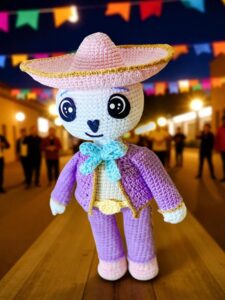 Don Cuco amigurumi mariachi posando frente a luces cálidas difuminadas