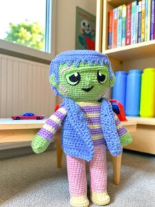 Diseño de monstruo de trapo tejido a crochet sentado en un estante de costura
