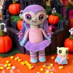 Personaje de cuento de vampira amigurumi rodeada de calabazas e iluminación cálida
