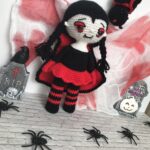 Vampirita amigurumi Isobel con cabello negro y trenzas en un escenario de Halloween