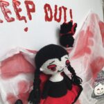 Patrón amigurumi vampira PDF de Isobel de pie junto al letrero Keep Out tejido