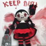 Muñeca de crochet de vampira kawaii con capa roja y negra en fondo festivo